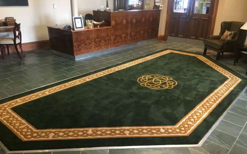 Hand tufted green rug with celtic border and motif in a hotel lobby